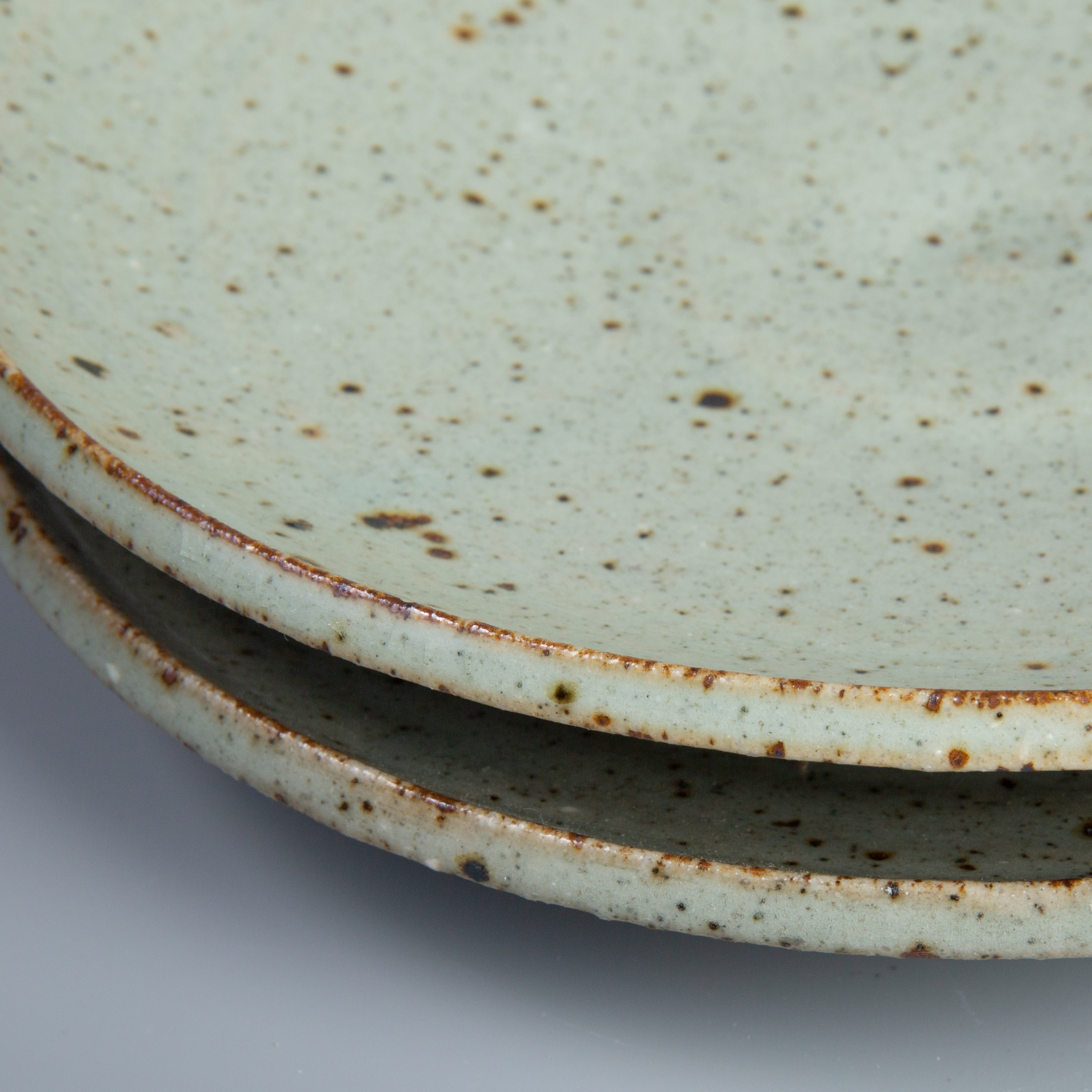Close-up of weathered hands shaping a ribbed clay vessel.